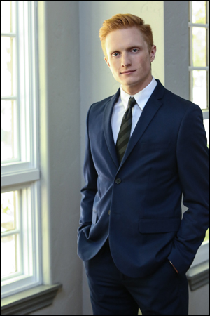 Young professional man standing in a business suit in the natural window light.  